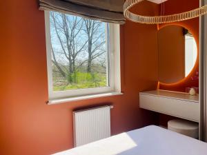 a bedroom with an orange wall and a window at Natura Iława Luxury Apartments in Iława