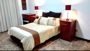 a bedroom with a bed with two night stands and a lamp at The Wynford Lodge in Summerstrand
