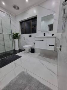 a white bathroom with a toilet and a shower at Luxury Secured Apartment in Centurion