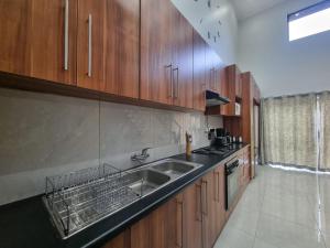 a kitchen with a sink and wooden cabinets at Luxury Secured Apartment in Centurion