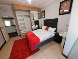 ein Schlafzimmer mit einem großen Bett mit einer roten Decke in der Unterkunft Van Buuren Lodge in Germiston