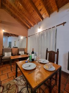 a wooden table with plates and wine glasses on it at Nagual -Ecolodge- Airport Shuttle & Restaurant in Tristán Suárez