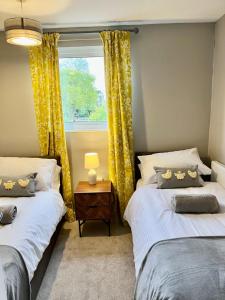 two beds in a room with a window at Canada House - Sleeps 6 -3 King or 6 Single Ideal for contractors in Warrington