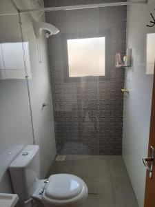 a bathroom with a toilet and a window at Casa de Praia a 550m da praia de Balneário Rosa do Mar e 350m da Lagoa da Tapera. in Passo de Torres