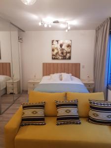 een slaapkamer met een bed en een gele bank met kussens bij Godoy House in Buenos Aires