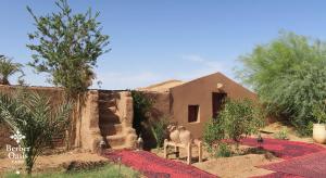 un hombre sentado en un banco frente a una casa en Berber Oasis Camp, en Oulad Driss