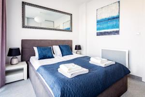 sypialnia z łóżkiem z niebieską pościelą i lustrem w obiekcie AWO Apartamenty w Łebie