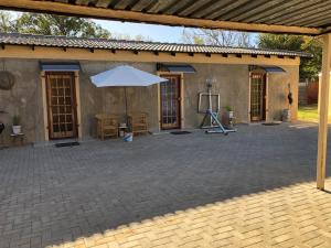 a patio with an umbrella and a table and chairs at Pozi Guest House in Sasolburg