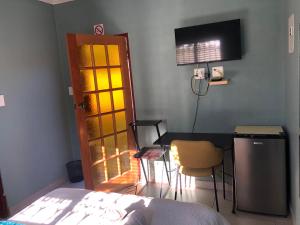 a bedroom with a bed and a desk and a door at Pozi Guest House in Sasolburg