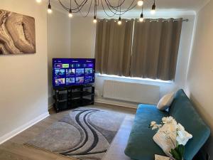 a living room with a couch and a flat screen tv at Lovely flat with Wi-Fi and free parking in Reading