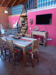 einen Tisch und Stühle in einem Zimmer mit einer rosa Wand in der Unterkunft CABAÑAS ALMA SERENA in Capilla del Monte