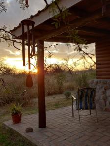 a chair sitting on a patio with the sunset in the background at CABAÑAS ALMA SERENA in Capilla del Monte