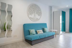 eine blaue Couch in einem Wohnzimmer mit einem Baumbild an der Wand in der Unterkunft La Perla del Sur - The Pearl House in Chayofa