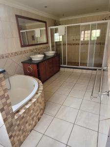 a bathroom with a tub and two sinks and a shower at Van Buuren Lodge in Germiston