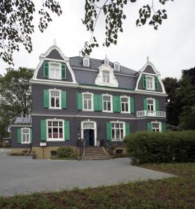 ein großes Haus mit Grün- und Weißtönen in der Unterkunft Hotel 1782 - Contactless self check-in in Remscheid