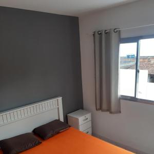 a bedroom with an orange bed and a window at Apartamento 204 vista para o mar e piscina in Piúma