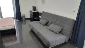 um sofá cinzento numa sala de estar com uma cama em Retiro das Camélias em Lajes das Flores