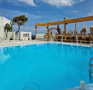 uma grande piscina azul com um bar ao fundo em Dawn Suites Santorini em Vourvoúlos