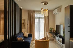 a living room with a blue couch and a tv at Embassy gardens Luxury suites CPG in Accra
