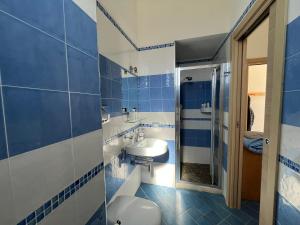 La salle de bains bleue et blanche est pourvue d'un lavabo et d'un miroir. dans l'établissement Veranda sul mare di Donnalucata, à Donnalucata