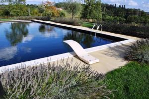 una piscina con un banco en un jardín en Château Les Merles et ses Villas en Mouleydier