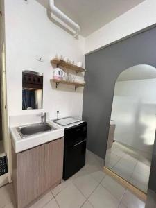 een kleine keuken met een wastafel en een douche bij Studio type Loft bed near Ortigas in Manilla