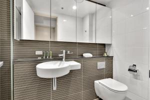 Baño blanco con lavabo y aseo en North Sydney Large Two Bedroom MIL2252402 en Sídney