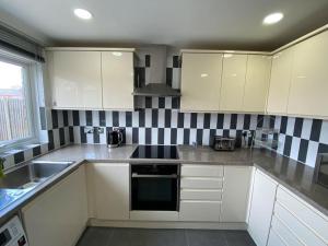 a kitchen with white cabinets and black and white tiles at Three bedrooms house in Windsor in Windsor