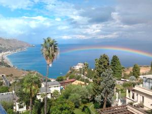 a rainbow over the ocean with houses and palm trees at The Dolphins Guest House in Taormina