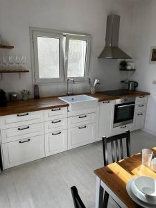 een keuken met witte kasten, een wastafel en een tafel bij Newly refurbished, coastal apartment- Barbati in Barbati