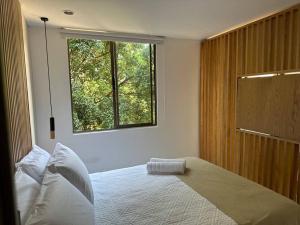 une chambre avec un grand lit avec une fenêtre dans l'établissement Exclusivo Loft en el poblado-rodeado de naturaleza 501, à Medellín