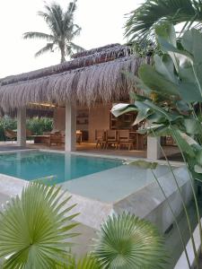 um resort com uma piscina e um telhado de palha em Villa Hele em General Luna
