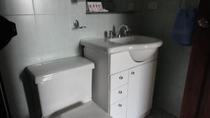 Baño blanco con lavabo y aseo en Hostel Del Piamonte 2, en Quito