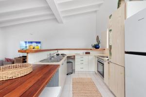 cocina con armarios blancos y encimera de madera en Castaway in Tugun en Gold Coast