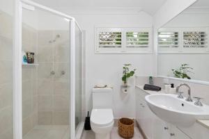 a white bathroom with a toilet and a sink at Castaway in Tugun in Gold Coast