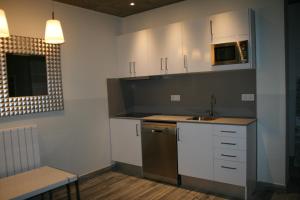 バニョラスにあるAlberg L'Astの白いキャビネット、シンク、電子レンジ付きのキッチンが備わります。