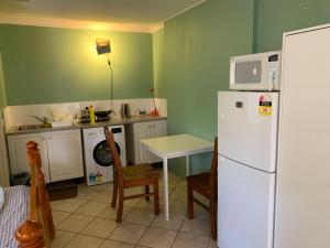 Il comprend une cuisine équipée d'un réfrigérateur blanc et d'une table avec des chaises. dans l'établissement lovey studio with bathroom and kitchen, à Perth