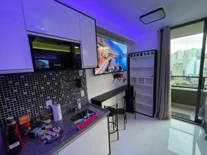 聖保羅的住宿－Oy Frei Caneca ap1502，一个带水槽的厨房和墙上的电视