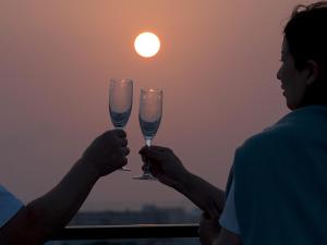 duas pessoas a segurar taças de champanhe em frente ao pôr-do-sol em HOTEL Y'RISE TO URASOE em Urazoe