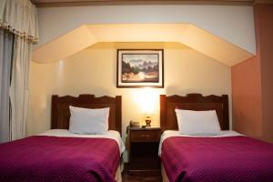 Habitación de hotel con 2 camas con sábanas moradas en Hotel Diamante Azul en La Paz