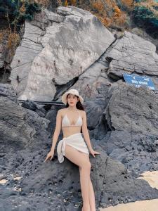 een vrouw in bikini zittend op een strand bij CÁT BÀ STORY HOMESTAY in Cat Ba