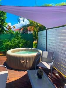 un bain à remous sur une terrasse avec une chaise et une table dans l'établissement Bungalow Ti Kako, à Capesterre-Belle-Eau