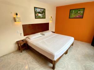 ein Bett in einem Schlafzimmer mit einer orangefarbenen Wand in der Unterkunft AMBAR Rooms in Campeche