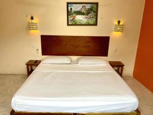 a bedroom with a large white bed with two tables at AMBAR Rooms in Campeche