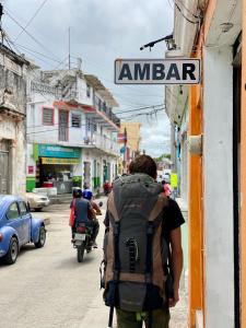 a man with a backpack walking down a street at AMBAR Rooms in Campeche