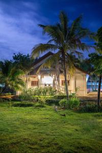 a house with palm trees in front of the ocean at Phubachiang Golf and Resort Pakse in Pakse