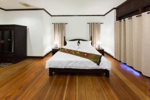 a bedroom with a large bed with wooden floors at Phubachiang Golf and Resort Pakse in Pakse