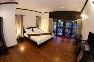 um quarto com uma cama e piso em madeira em Phubachiang Golf and Resort Pakse em Pakse