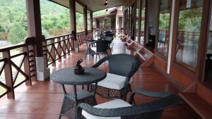 a balcony with tables and chairs on a building at Phubachiang Golf and Resort Pakse in Pakse