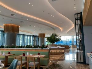 un restaurant avec des tables, des chaises et des fenêtres dans l'établissement HB Serviced Apartment - Alacarte Hạ Long, à Hạ Long